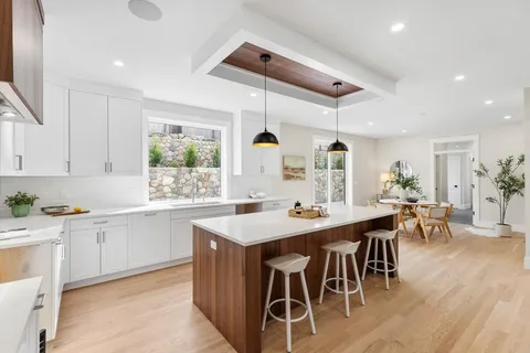 a kitchen with stainless steel appliances a dining table chairs stove and white cabinets