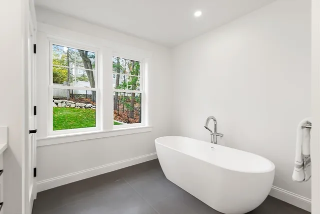 a white bath tub sitting in a bathroom next to a window