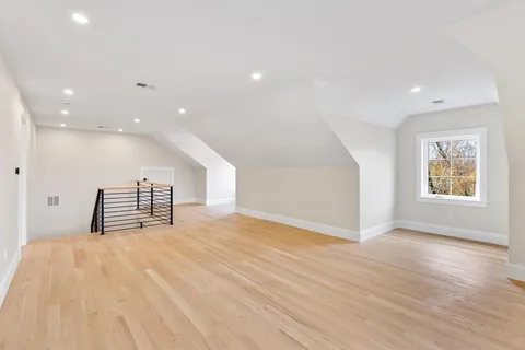 a view of an empty room with wooden floor and windows