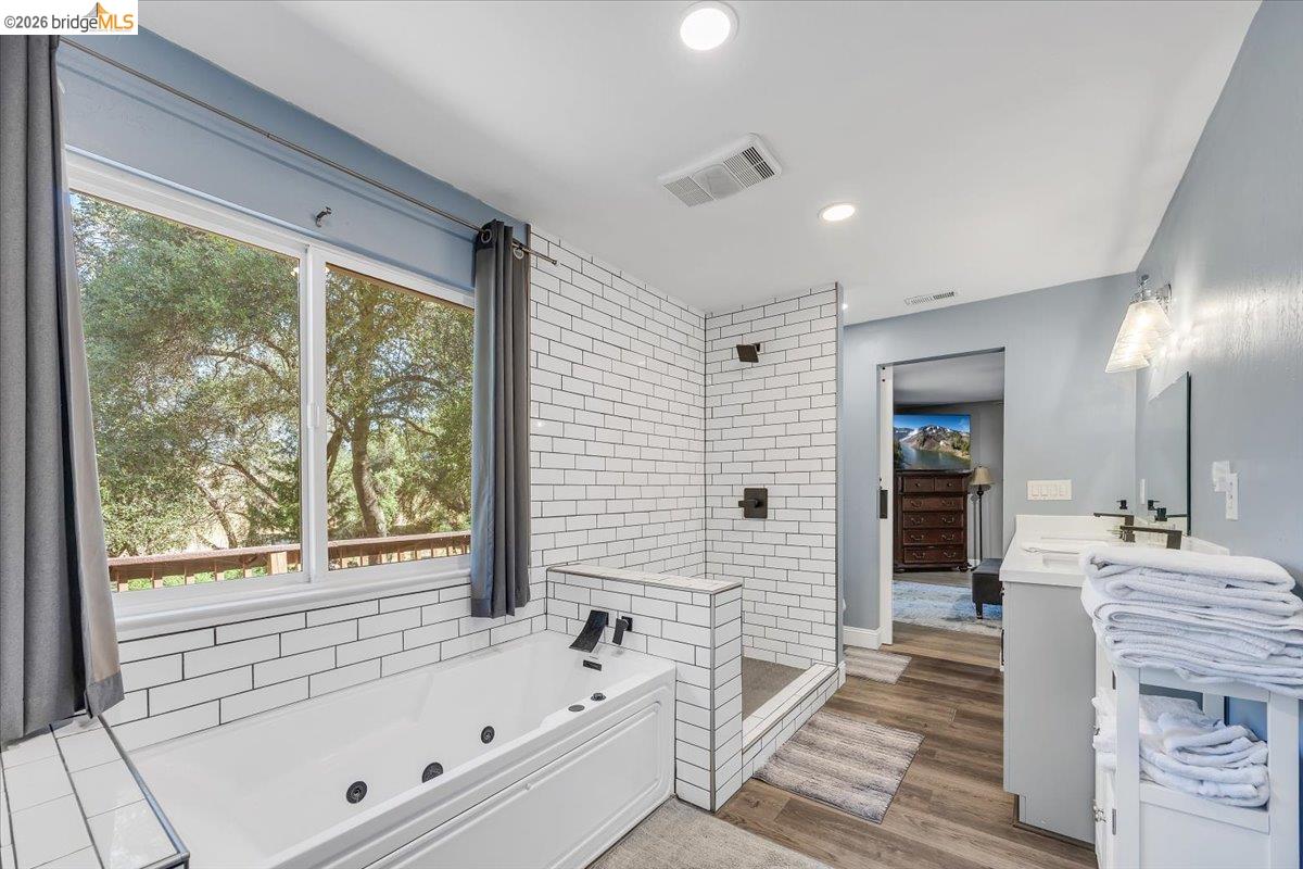 8733 Fraguero Road Sonora, CA 95370 - Photo 46 of 73 Bathroom featuring a jetted soaking tub, walk-in shower with subway tile surround, and dual vanity with black fixtures