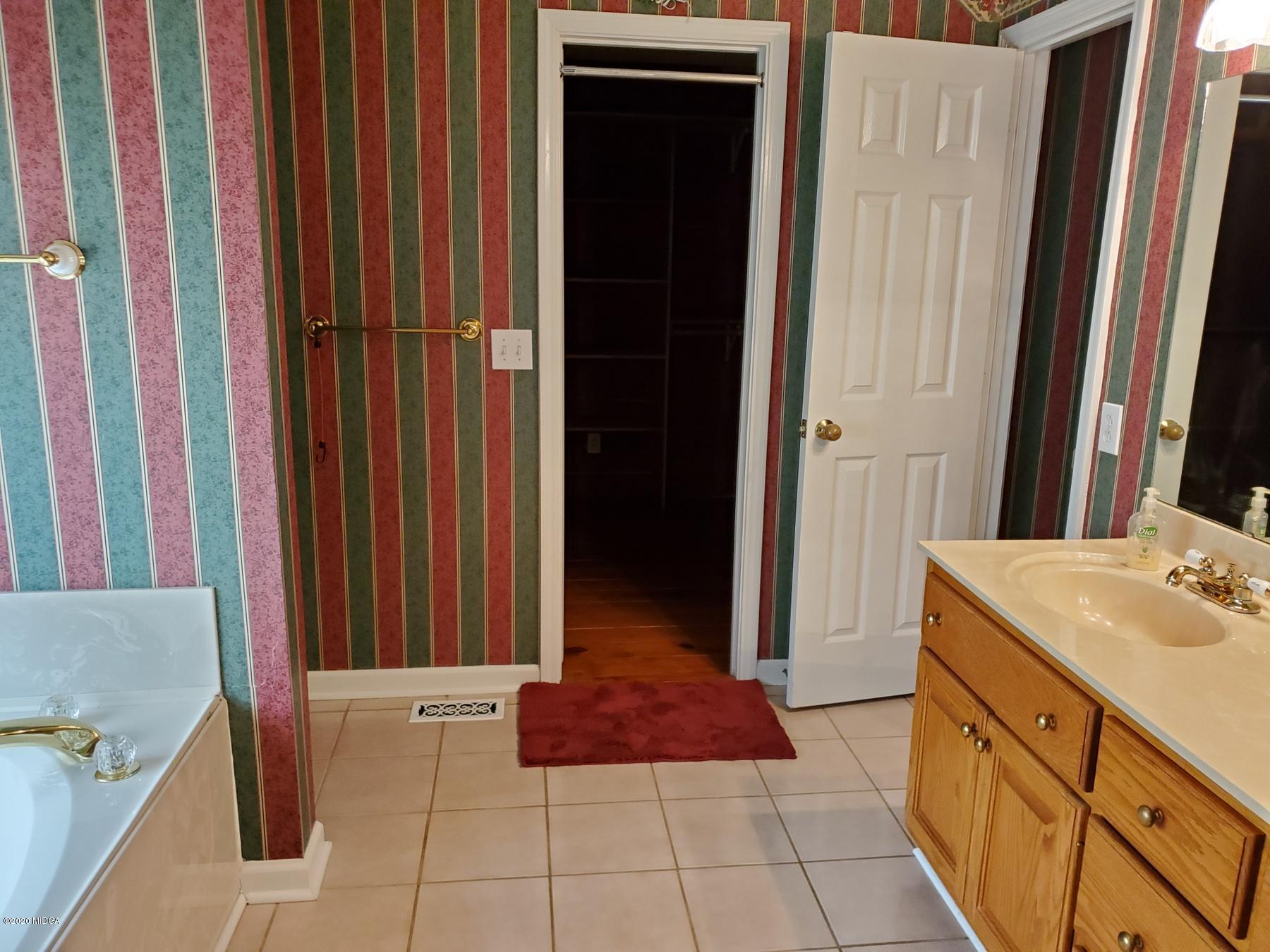 144 Gates Road Lizella, GA 31052 - Photo 28 of 44 a spacious bathroom with a granite countertop sink and a mirror