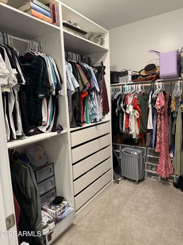 a view of walk in closet with clothes and shoes