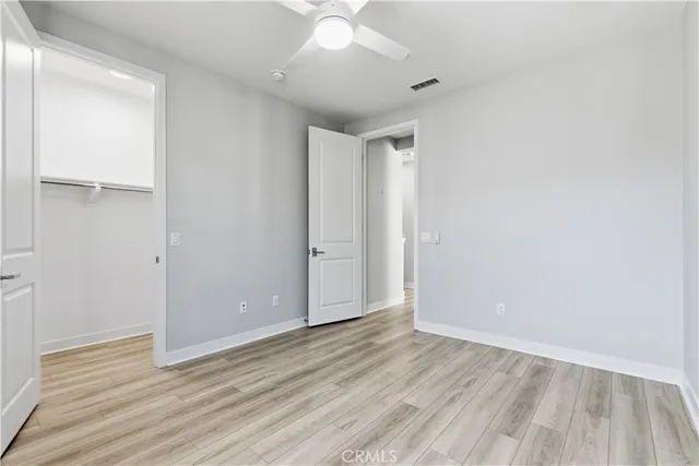 an empty room with wooden floor and fan