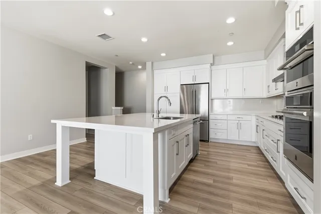 a view of a kitchen with a dishwasher kitchen island wooden floor and a refrigerator