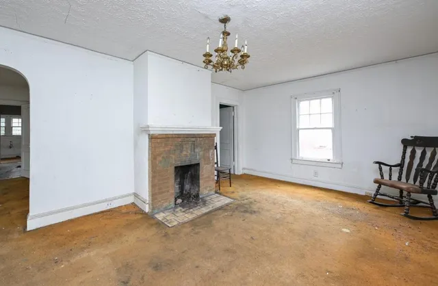 an empty room with windows and fireplace