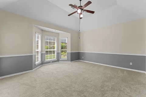 a view of an empty room with a ceiling fan and window