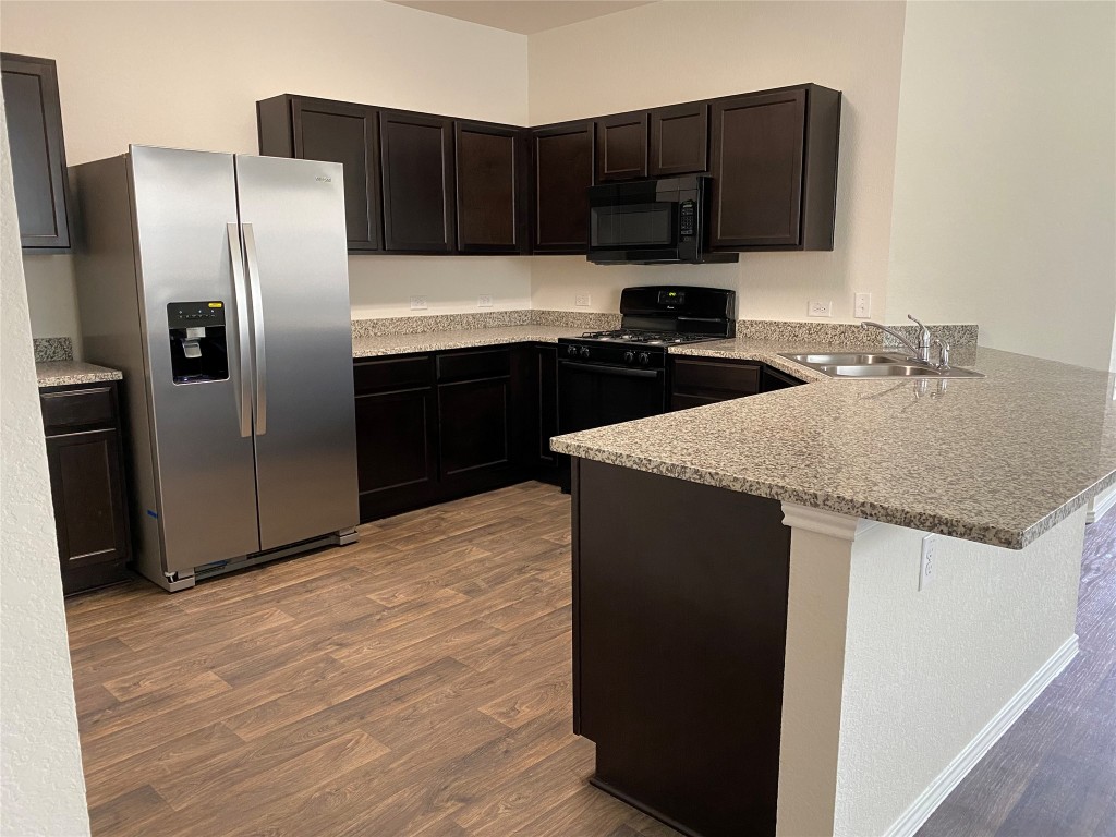 3607 Conyers Lane Austin, TX 78725 - Photo 2 of 24 a kitchen with kitchen island granite countertop a refrigerator and a sink