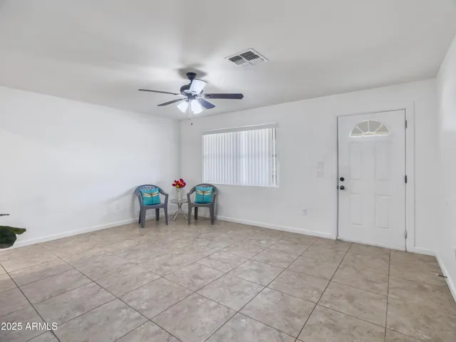 a view of an empty room and chandelier fan