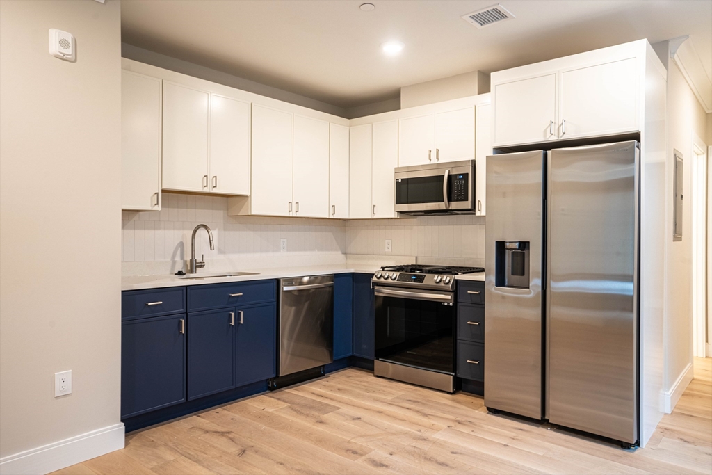 157 Everett Street, Unit 102 Boston, MA 02134 - Photo 2 of 7 a kitchen with stainless steel appliances granite countertop a refrigerator and a stove top oven