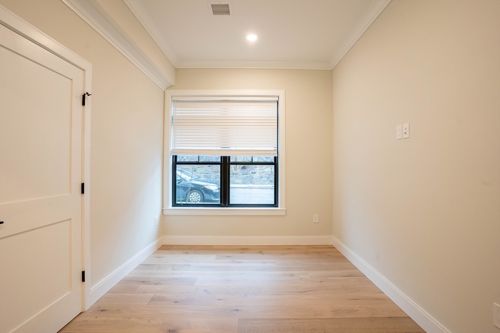 157 Everett Street, Unit 102 Boston, MA 02134 - Photo 4 of 7 an empty room with wooden floor and windows