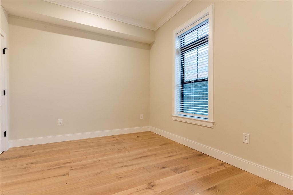 157 Everett Street, Unit 102 Boston, MA 02134 - Photo 5 of 7 a view of an empty room with wooden floor and a window