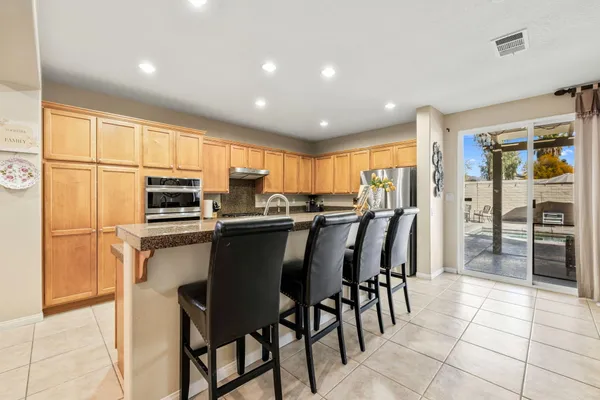 a kitchen with stainless steel appliances kitchen island granite countertop a table chairs microwave and sink