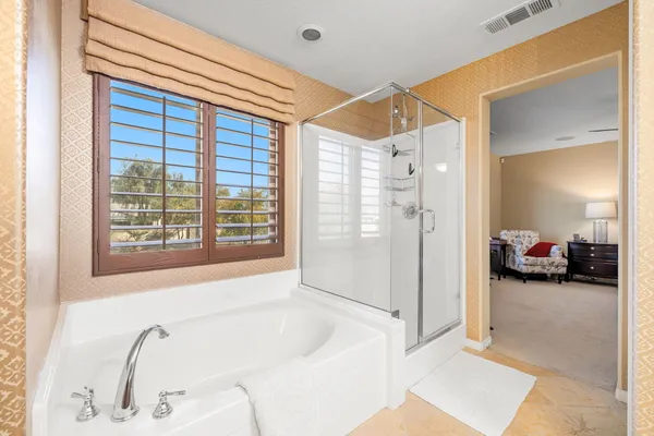 a bathroom with a tub a sink and a large mirror next to a window
