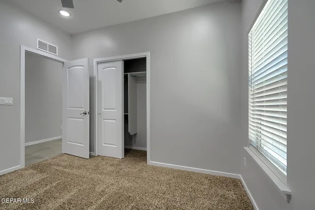 an empty room with a ceiling fan and a window