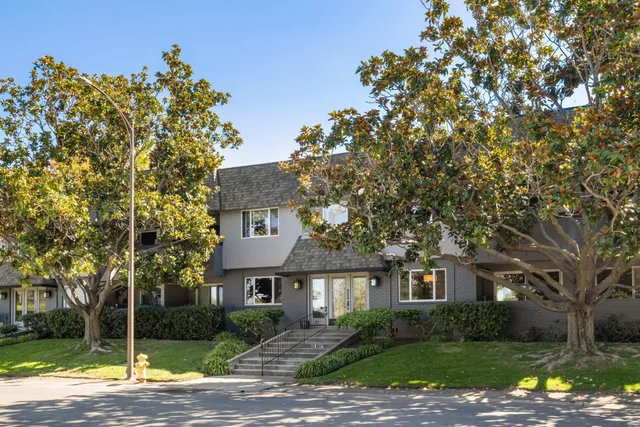 a front view of a house with a garden and tree