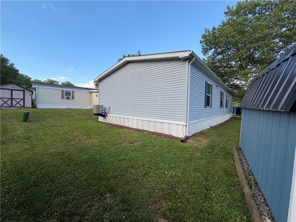 12 Springridge Road Bath, PA 18014 - Photo 36 of 61 A manufactured home with light blue siding stands on a well-maintained lawn, flanked by utility sheds.