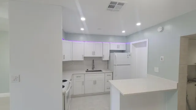 a kitchen that has a refrigerator a sink and white cabinets