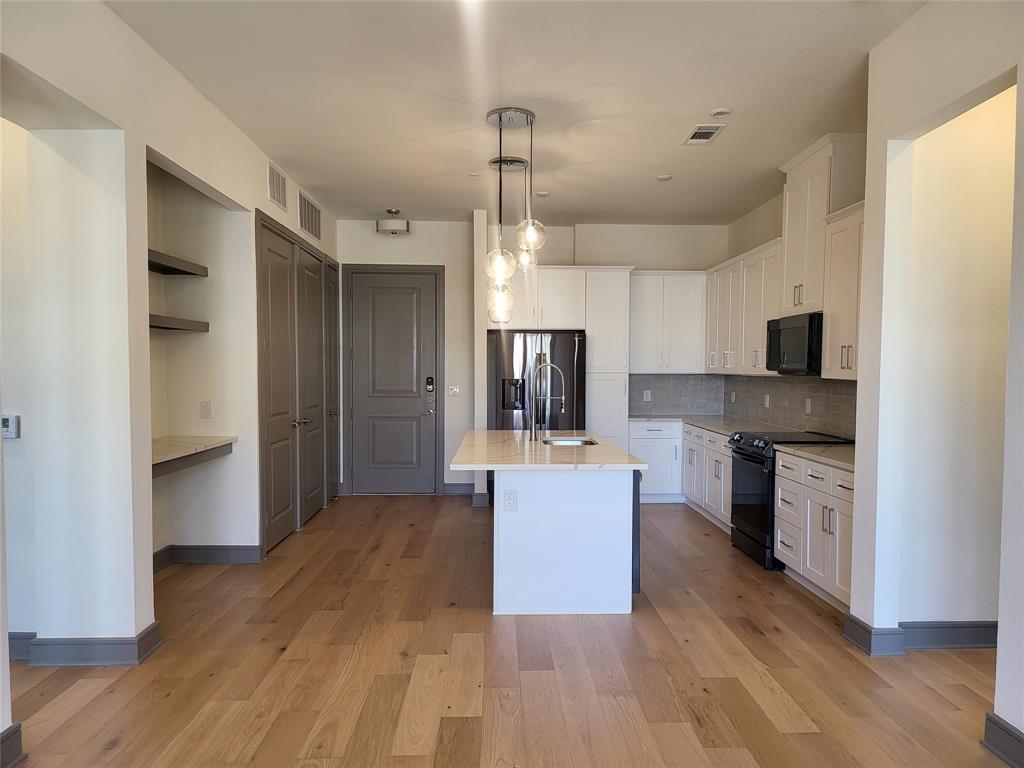 2700 Old Denton Road, Unit 2233 Carrollton, TX 75007 - Photo 2 of 13 a large kitchen with cabinets wooden floor and stainless steel appliances