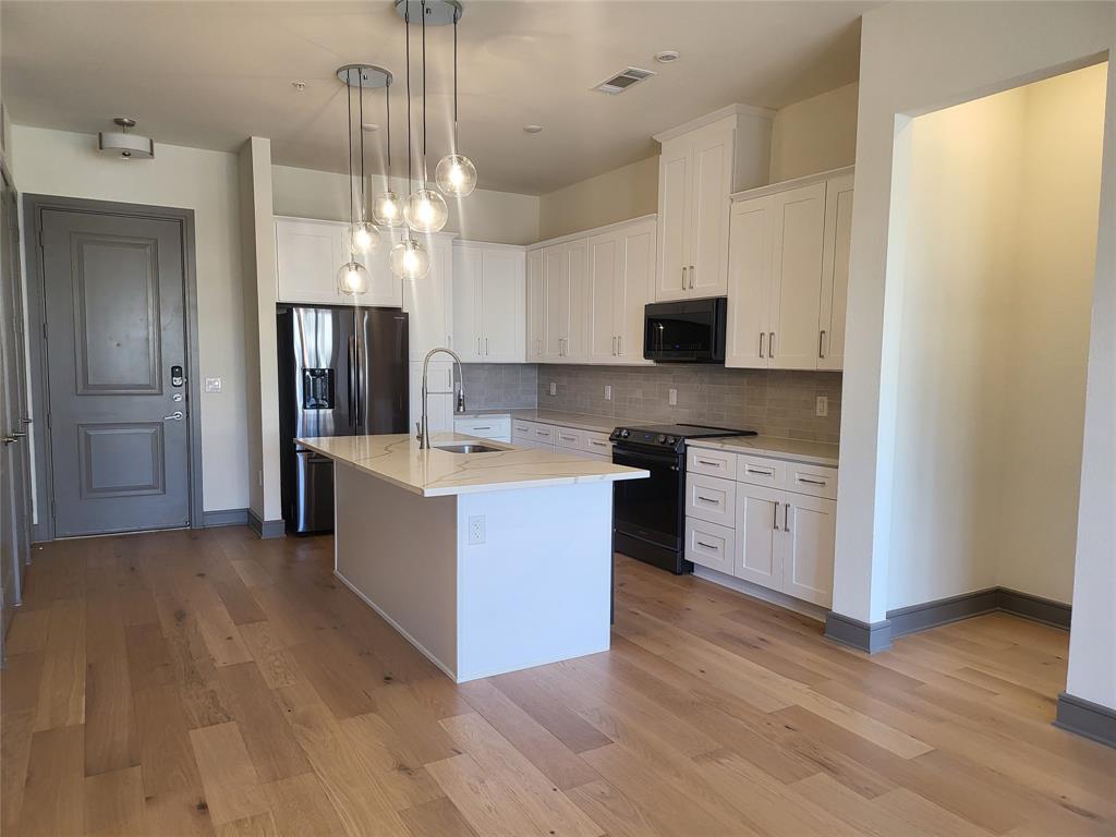2700 Old Denton Road, Unit 2233 Carrollton, TX 75007 - Photo 8 of 13 a large kitchen with stainless steel appliances kitchen island granite countertop a stove and a refrigerator
