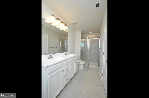 a bathroom with a double vanity sink and mirror with shower