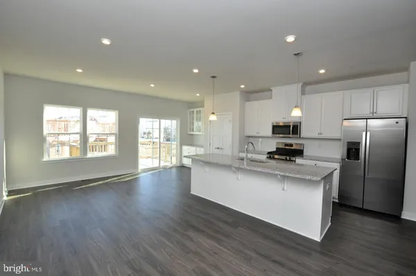 a large kitchen with stainless steel appliances a large window a wooden floor and a sink