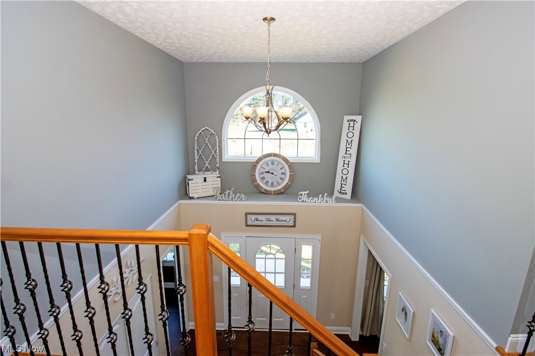 4750 McCauley Road Wooster, OH 44691 - Photo 22 of 37 Stairway with a textured ceiling, plenty of natural light, a chandelier, and wood-type flooring