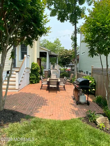 a backyard of a house with table and chairs plants and large tree