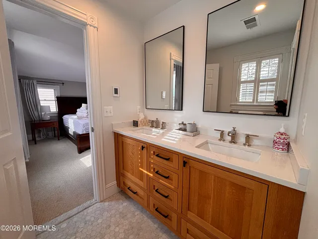 a en suite bathroom with a double vanity sink and a mirror
