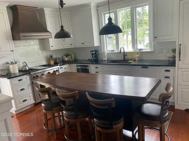 a kitchen with kitchen island a dining table chairs cabinets and a sink