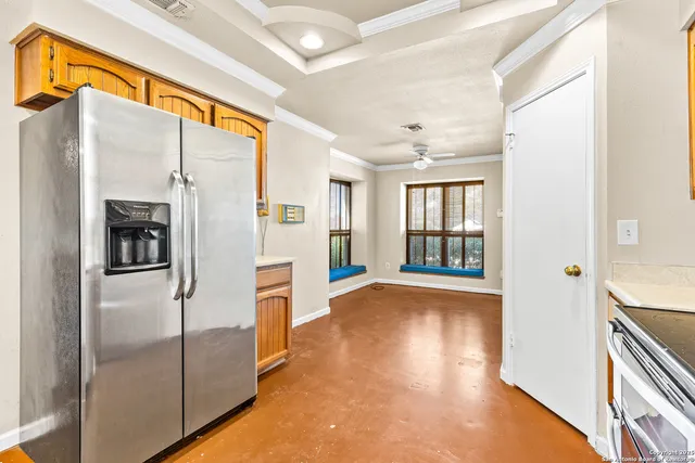 a view of a refrigerator in kitchen and an empty room