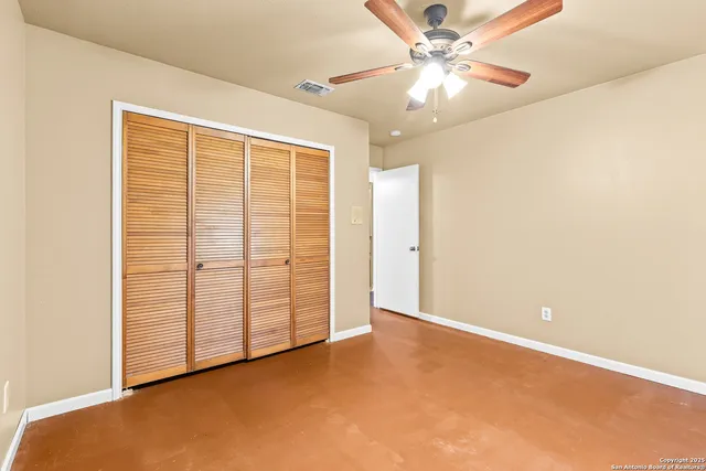 an empty room with windows and fan
