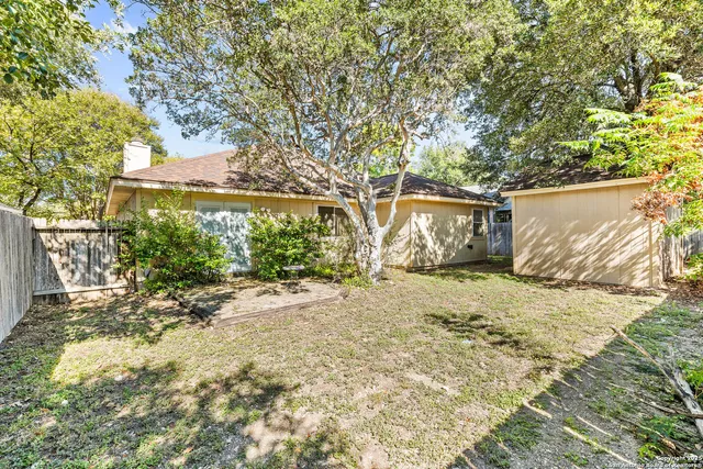 a backyard of a house with large trees and outdoor seating
