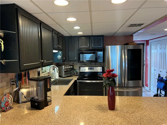 a kitchen with stainless steel appliances kitchen island granite countertop a refrigerator and a stove