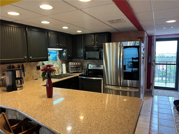 a kitchen with stainless steel appliances kitchen island granite countertop a refrigerator and a sink
