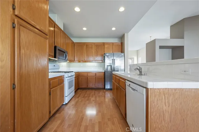 a kitchen with stainless steel appliances granite countertop a sink a stove a refrigerator cabinets and wooden floor