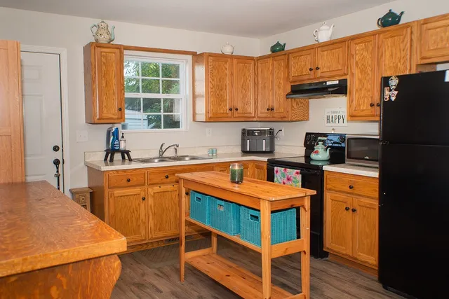 a kitchen with stainless steel appliances granite countertop a refrigerator a sink dishwasher a stove and white countertops with wooden floor