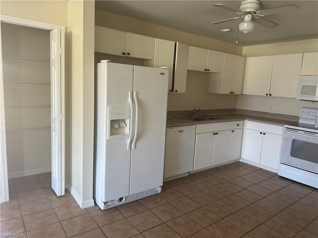 3965 20th Street West Lehigh Acres, FL 33971 - Photo 7 of 18 a kitchen with white cabinets and white appliances