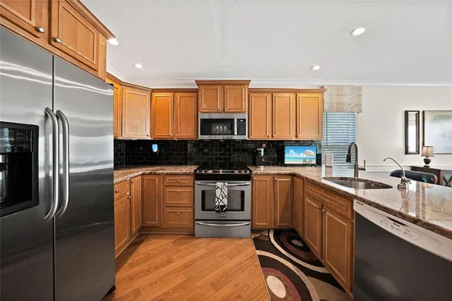 a kitchen with stainless steel appliances granite countertop a stove a sink and a refrigerator
