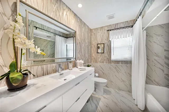 a bathroom with a double vanity sink a toilet a mirror and shower