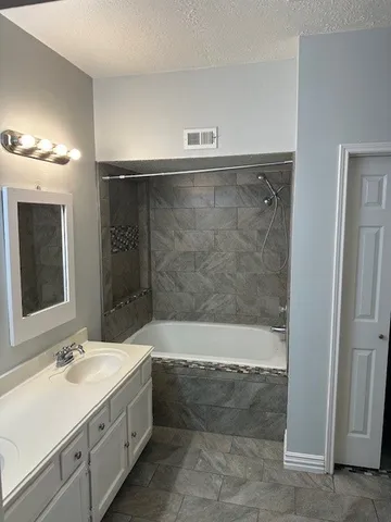 a bathroom with a double vanity sink mirror and bathtub