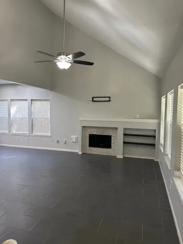 a view of a livingroom with a fireplace a ceiling fan and wooden floor