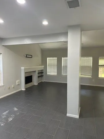 an empty room with windows and fireplace