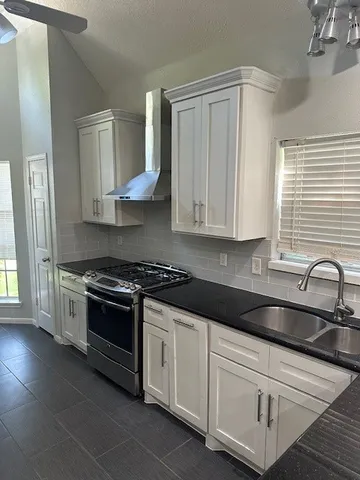 a kitchen with granite countertop white cabinets and stainless steel appliances