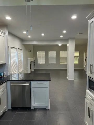 a large kitchen with granite countertop a sink and white cabinets