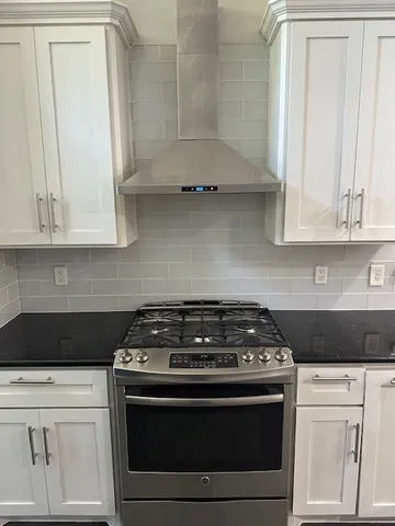 a kitchen with granite countertop white cabinets and black stove