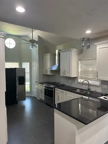 a kitchen with stainless steel appliances granite countertop a sink a stove and a refrigerator