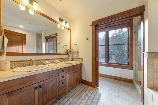 a spacious bathroom with a double vanity sink a mirror and a shower