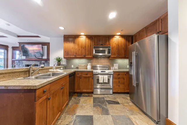 a kitchen with stainless steel appliances granite countertop a refrigerator and a sink