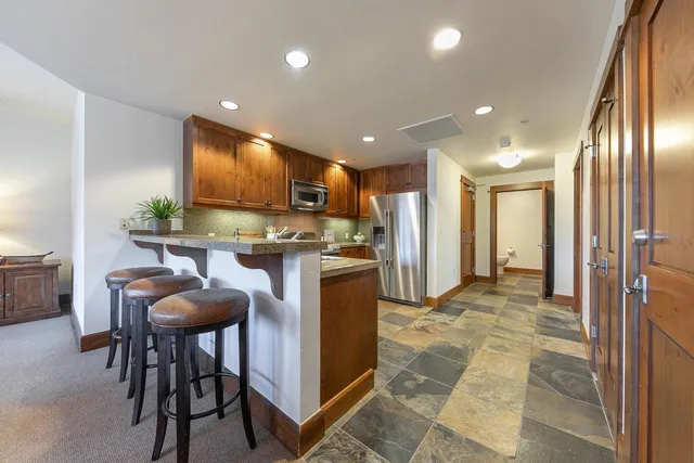 a open kitchen with kitchen island granite countertop wooden cabinets and stainless steel appliances