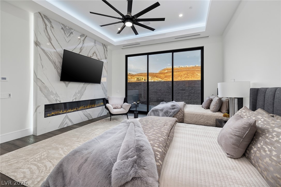 611 Cityview Ridge Drive Henderson, NV 89012 - Photo 50 of 66 Sliding glass doors reveal desert hill views from a bedroom featuring a modern stone fireplace.